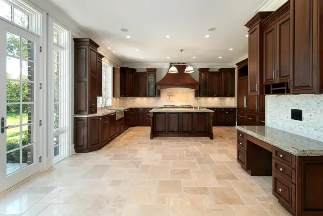 Elegant kitchen with a dark wood island and travertine tile flooring.